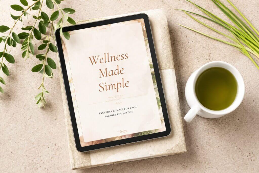 Tablet showing Wellness Made Simple beside a cup of green tea and plants
